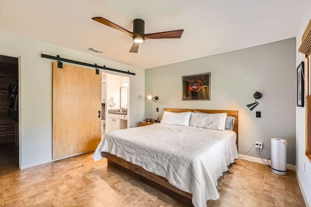 bedroom with visible vents, baseboards, a barn door, ensuite bathroom, and a ceiling fan