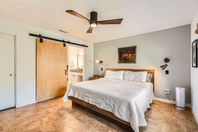 bedroom with visible vents, connected bathroom, baseboards, ceiling fan, and a barn door