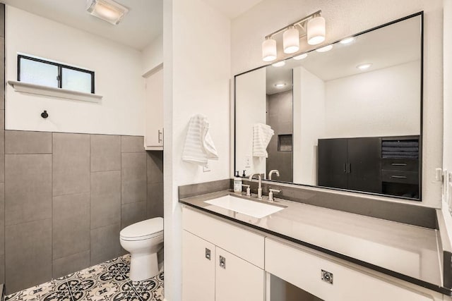 bathroom with toilet, tile walls, vanity, and tile patterned flooring