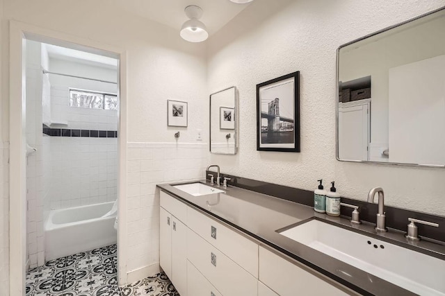 full bathroom featuring double vanity, tile patterned flooring, tile walls, and a sink