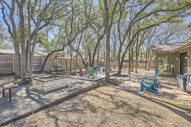 view of yard featuring a patio area, a fire pit, and fence