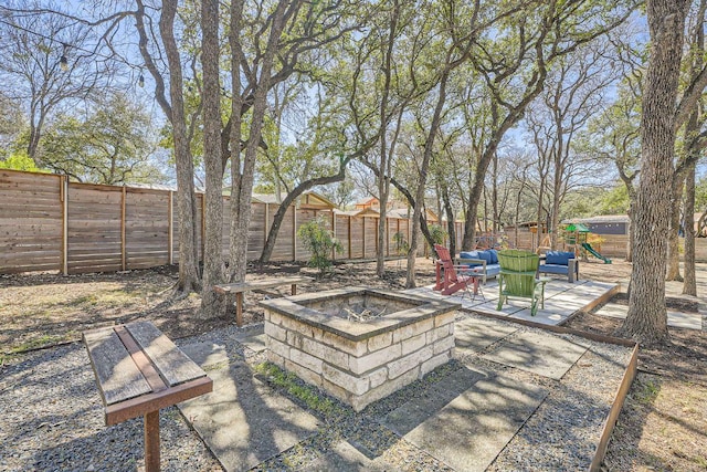 view of yard featuring a patio area, a fire pit, a playground, and a fenced backyard