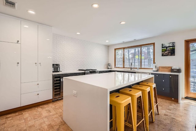 kitchen with a breakfast bar area, visible vents, a kitchen island, a sink, and light countertops