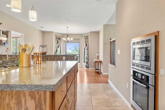 149 Colovista Dr, Bastrop, TX 78602 - kitchen featuring stainless steel appliances, a chandelier, brown cabinetry, and stone counters
