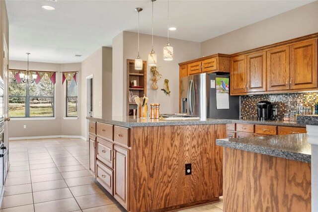 149 Colovista Dr, Bastrop, TX 78602 - kitchen featuring stainless steel fridge, brown cabinets, a kitchen island, light tile patterned floors, and backsplash