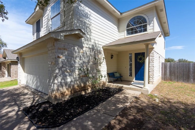 view of front facade featuring stone siding, concrete driveway, an attached garage, and fence