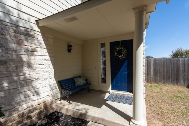 view of exterior entry with visible vents and fence