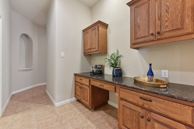 2812 Prosperity, Leander, TX 78641 - kitchen with brown cabinetry, baseboards, light tile patterned flooring, and dark stone countertops