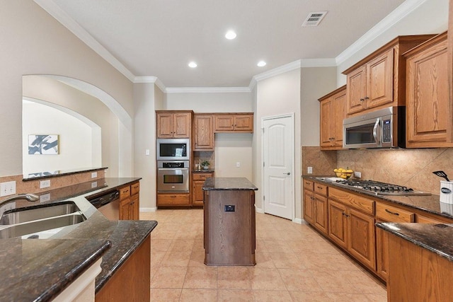 2812 Prosperity, Leander, TX 78641 - kitchen featuring stainless steel appliances, brown cabinets, a sink, ornamental molding, and dark stone countertops