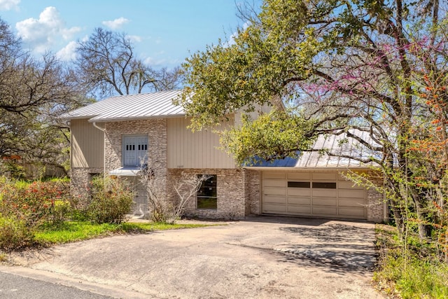 view of front of home featuring a standing seam roof, driveway, metal roof, and a garage