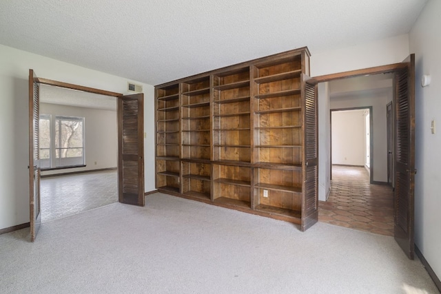 carpeted empty room with visible vents, a textured ceiling, and baseboards