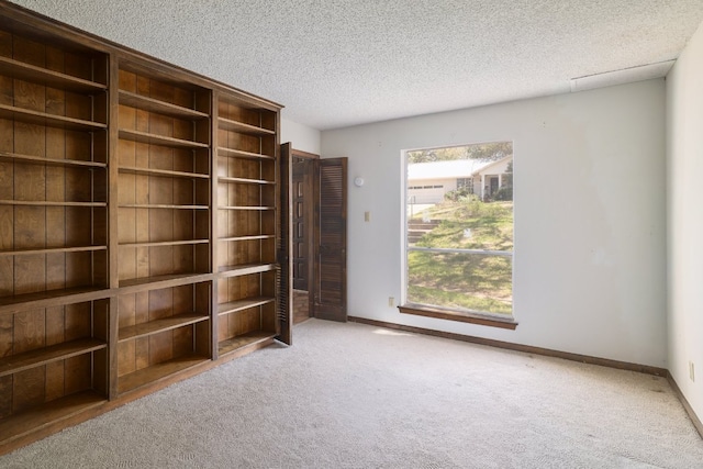 carpeted spare room with baseboards and a textured ceiling