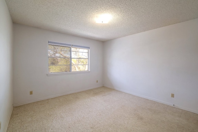 empty room featuring a textured ceiling and baseboards