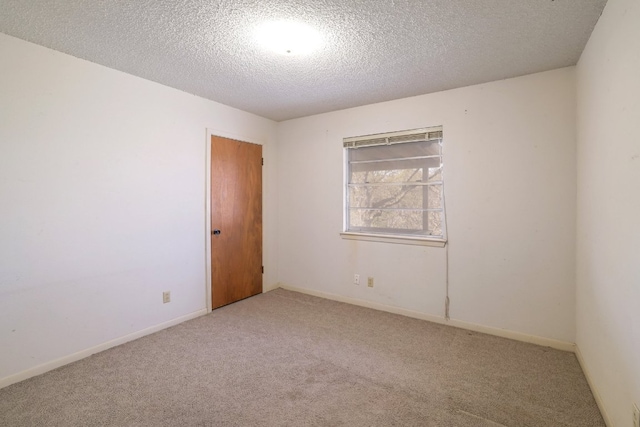 spare room with baseboards, a textured ceiling, and carpet