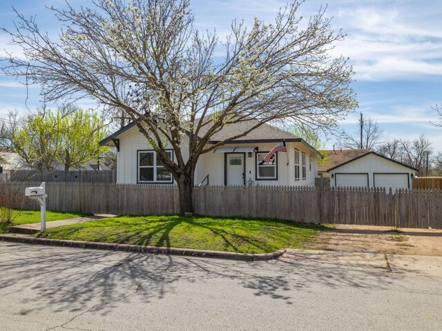 1401 W 7th St, Taylor, TX 76574 - bungalow featuring a fenced front yard, a detached garage, and an outdoor structure
