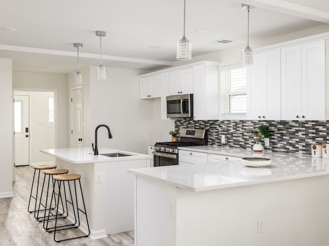 1401 W 7th St, Taylor, TX 76574 - kitchen featuring appliances with stainless steel finishes, light wood-type flooring, decorative backsplash, and a breakfast bar