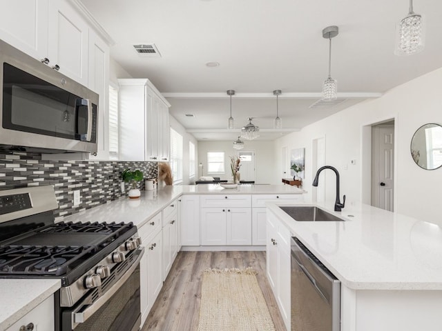 1401 W 7th St, Taylor, TX 76574 - kitchen with appliances with stainless steel finishes, light wood-style floors, white cabinetry, backsplash, and pendant lighting