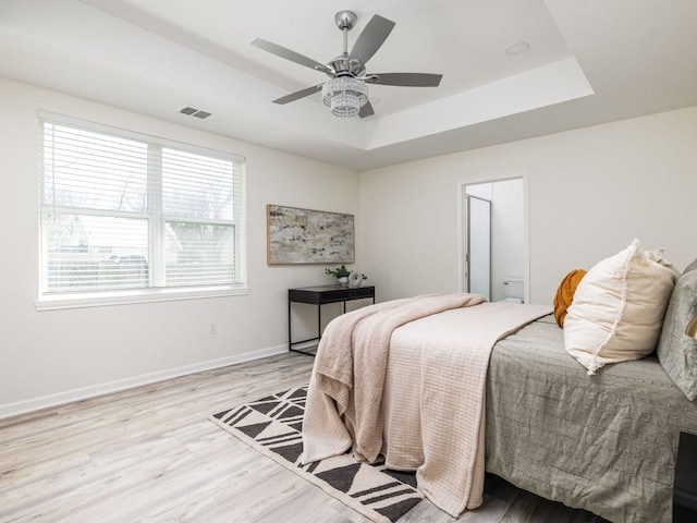 1401 W 7th St, Taylor, TX 76574 - bedroom with multiple windows, a tray ceiling, light wood-style flooring, and a ceiling fan