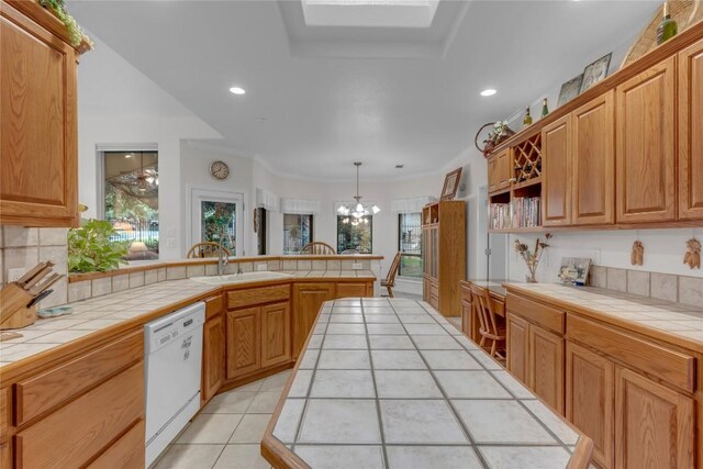 201 Lasso, Horseshoe Bay, TX 78657 - kitchen with white dishwasher, tile counters, a chandelier, a peninsula, and decorative backsplash
