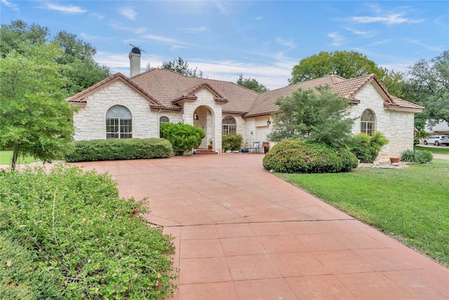 201 Lasso, Horseshoe Bay, TX 78657 - french country home featuring stone siding, a garage, a tile roof, driveway, and a front lawn