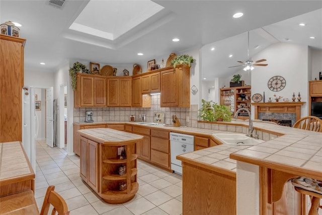 201 Lasso, Horseshoe Bay, TX 78657 - kitchen with white dishwasher, tile countertops, a tiled fireplace, backsplash, and a ceiling fan