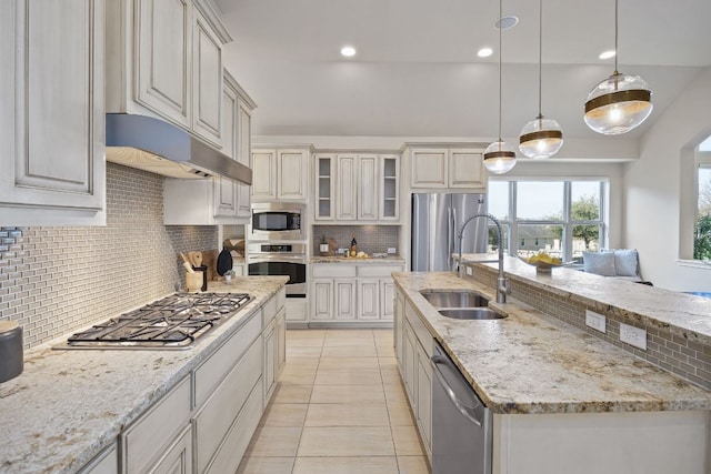14320 Senia Bnd, Austin, TX 78738 - kitchen with a sink, tasteful backsplash, light stone counters, appliances with stainless steel finishes, and an island with sink