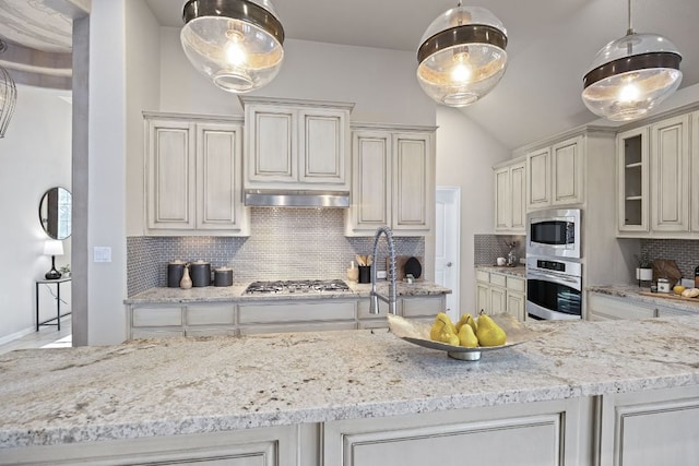14320 Senia Bnd, Austin, TX 78738 - kitchen featuring appliances with stainless steel finishes, light stone counters, tasteful backsplash, lofted ceiling, and glass insert cabinets