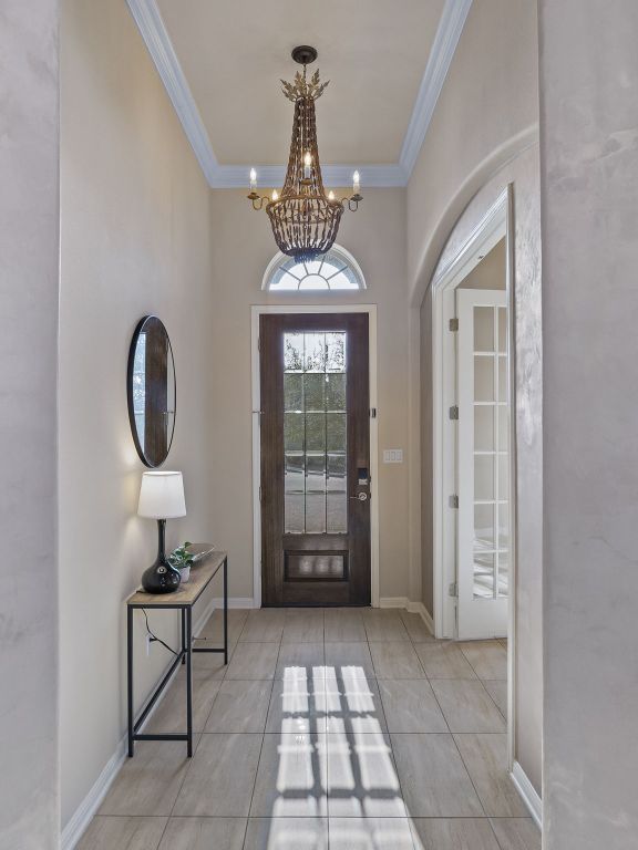 14320 Senia Bnd, Austin, TX 78738 - entrance foyer featuring crown molding, arched walkways, a chandelier, tile patterned floors, and baseboards