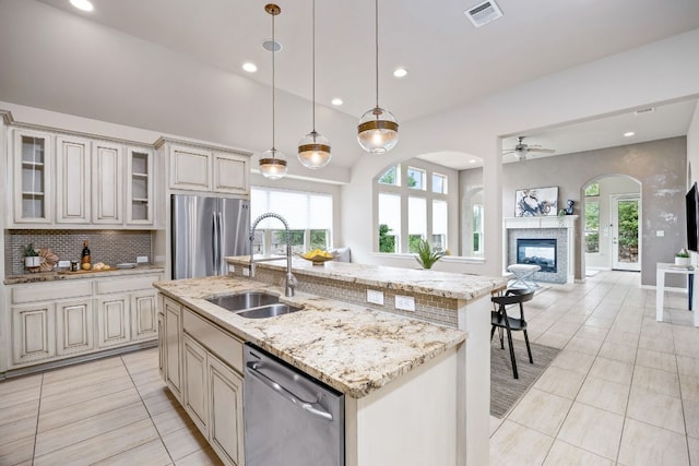 14320 Senia Bnd, Austin, TX 78738 - kitchen with stainless steel appliances, light tile patterned floors, a glass covered fireplace, visible vents, and arched walkways
