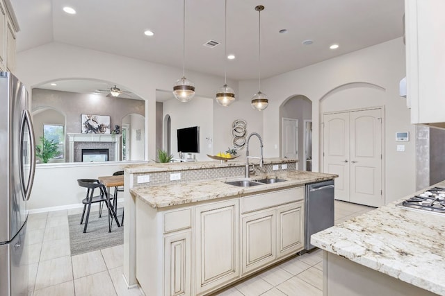 14320 Senia Bnd, Austin, TX 78738 - kitchen featuring arched walkways, stainless steel appliances, a sink, a ceiling fan, and a fireplace