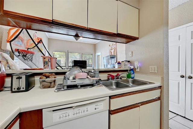 kitchen featuring dishwasher, light countertops, a textured wall, and a sink