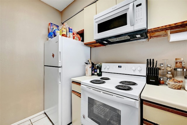 kitchen with white cabinetry, white appliances, light tile patterned flooring, and light countertops