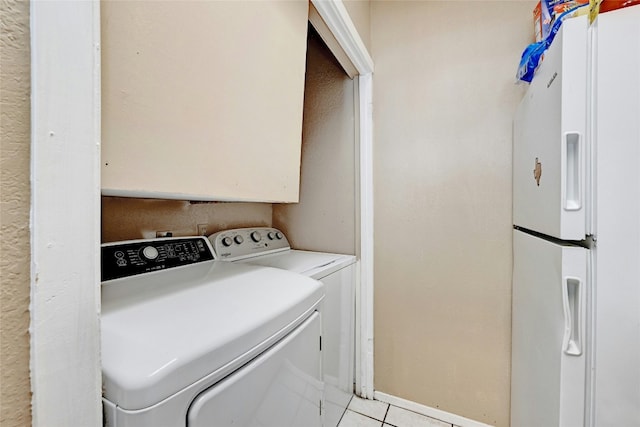 clothes washing area featuring laundry area, light tile patterned floors, baseboards, and washer and clothes dryer