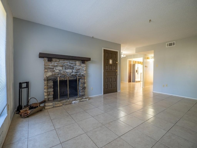 unfurnished living room with light tile patterned floors, visible vents, a textured ceiling, and a fireplace