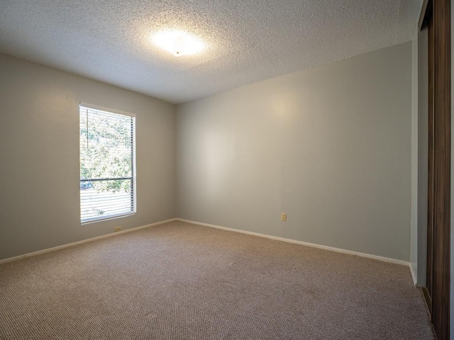 carpeted empty room featuring baseboards and a textured ceiling