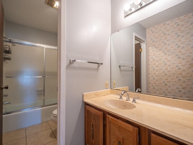 bathroom with tile patterned floors, toilet, a textured ceiling, bath / shower combo with glass door, and vanity