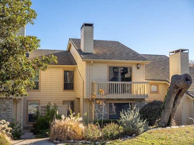 rear view of house featuring a chimney and a balcony