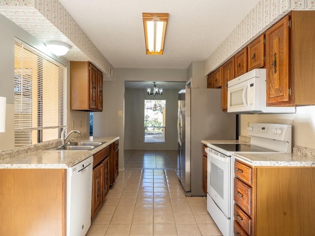 kitchen featuring light tile patterned flooring, white appliances, light countertops, and a sink