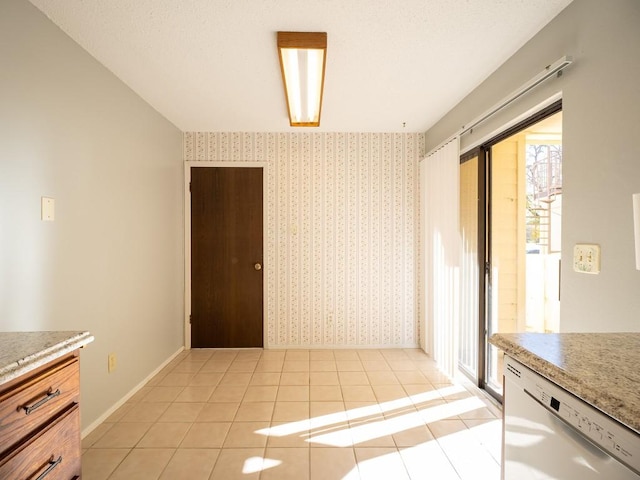 kitchen featuring light tile patterned floors, dishwasher, wallpapered walls, and baseboards