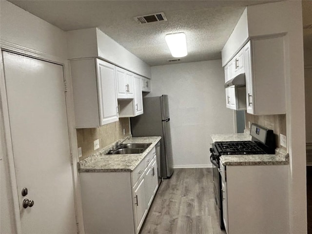 6705 Skynook Dr, Austin, TX 78745 - kitchen with appliances with stainless steel finishes, light wood-type flooring, light countertops, a textured ceiling, and white cabinetry