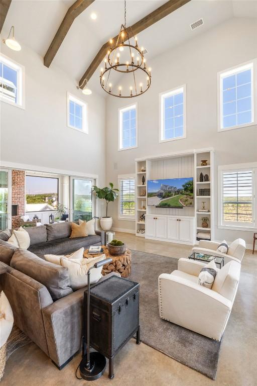 living area featuring a notable chandelier, visible vents, a healthy amount of sunlight, and high vaulted ceiling