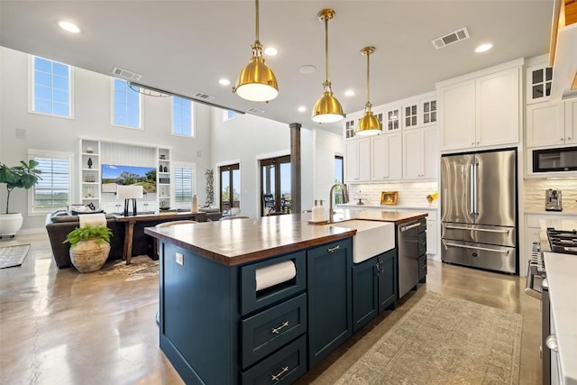 kitchen with a sink, white cabinets, visible vents, and stainless steel appliances