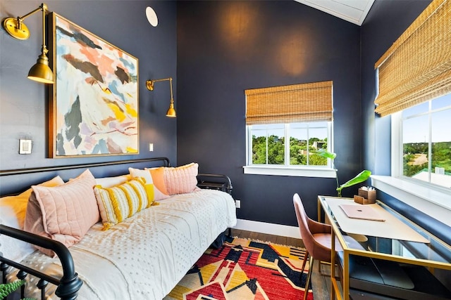 bedroom with multiple windows, baseboards, and wood finished floors