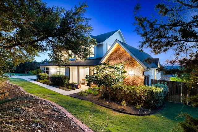 view of home's exterior featuring brick siding, fence, and a lawn