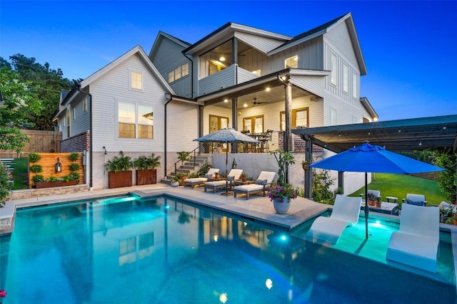 back of property featuring fence, board and batten siding, a fenced in pool, a balcony, and a patio area