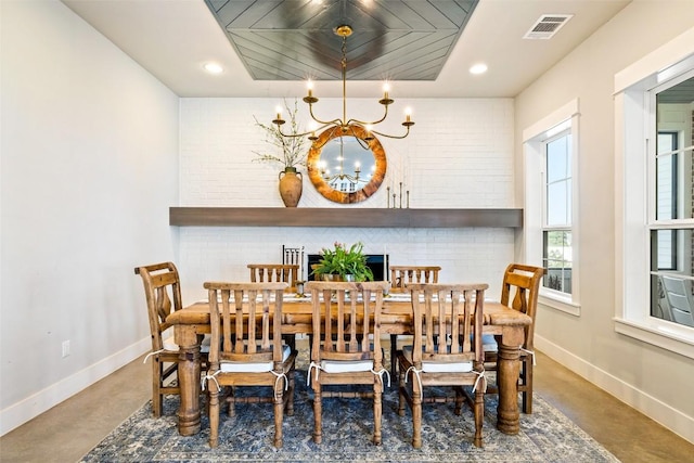 dining room with a chandelier, visible vents, brick wall, and baseboards