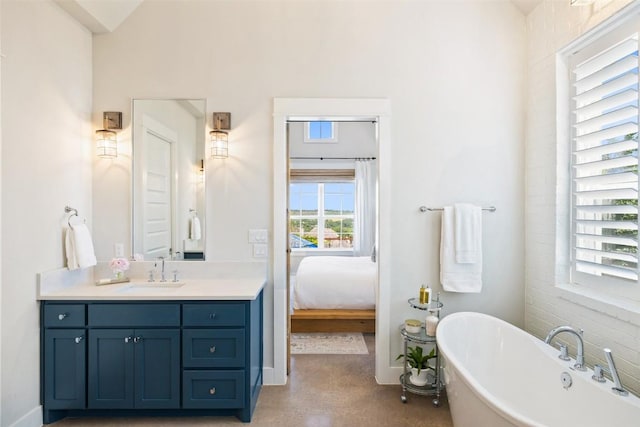 ensuite bathroom with vanity, a freestanding tub, baseboards, and ensuite bathroom