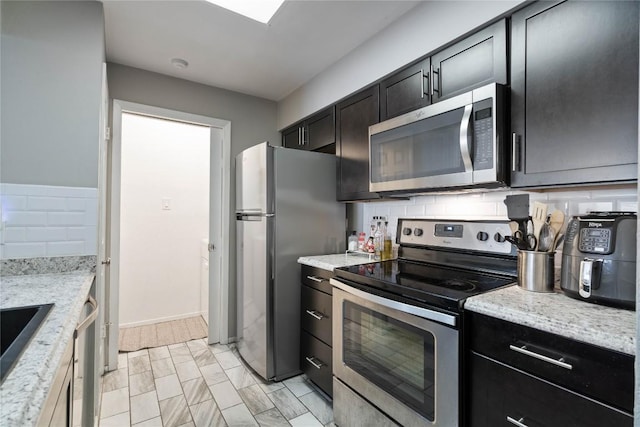807 W 25th St Unit 307, Austin, TX 78705 - kitchen featuring appliances with stainless steel finishes, tasteful backsplash, a sink, baseboards, and light stone counters