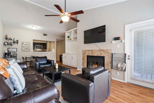 807 W 25th St Unit 307, Austin, TX 78705 - living room featuring ceiling fan, light wood finished floors, a tile fireplace, vaulted ceiling, and baseboards