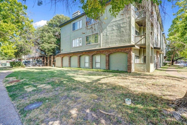 807 W 25th St Unit 307, Austin, TX 78705 - view of side of property featuring stucco siding, a balcony, a lawn, and brick siding